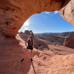 Gabby is standing in an arch at Moab exploring Arches National Park.